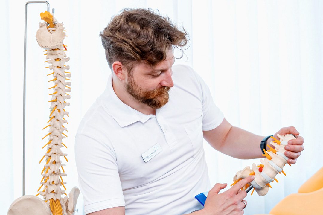 Fachliche Beratung: Physiotherapeut erklärt Behandlung der Bandscheibe am Wirbelsäulenmodell; RehaCity Basel. | SR-STUDIOS