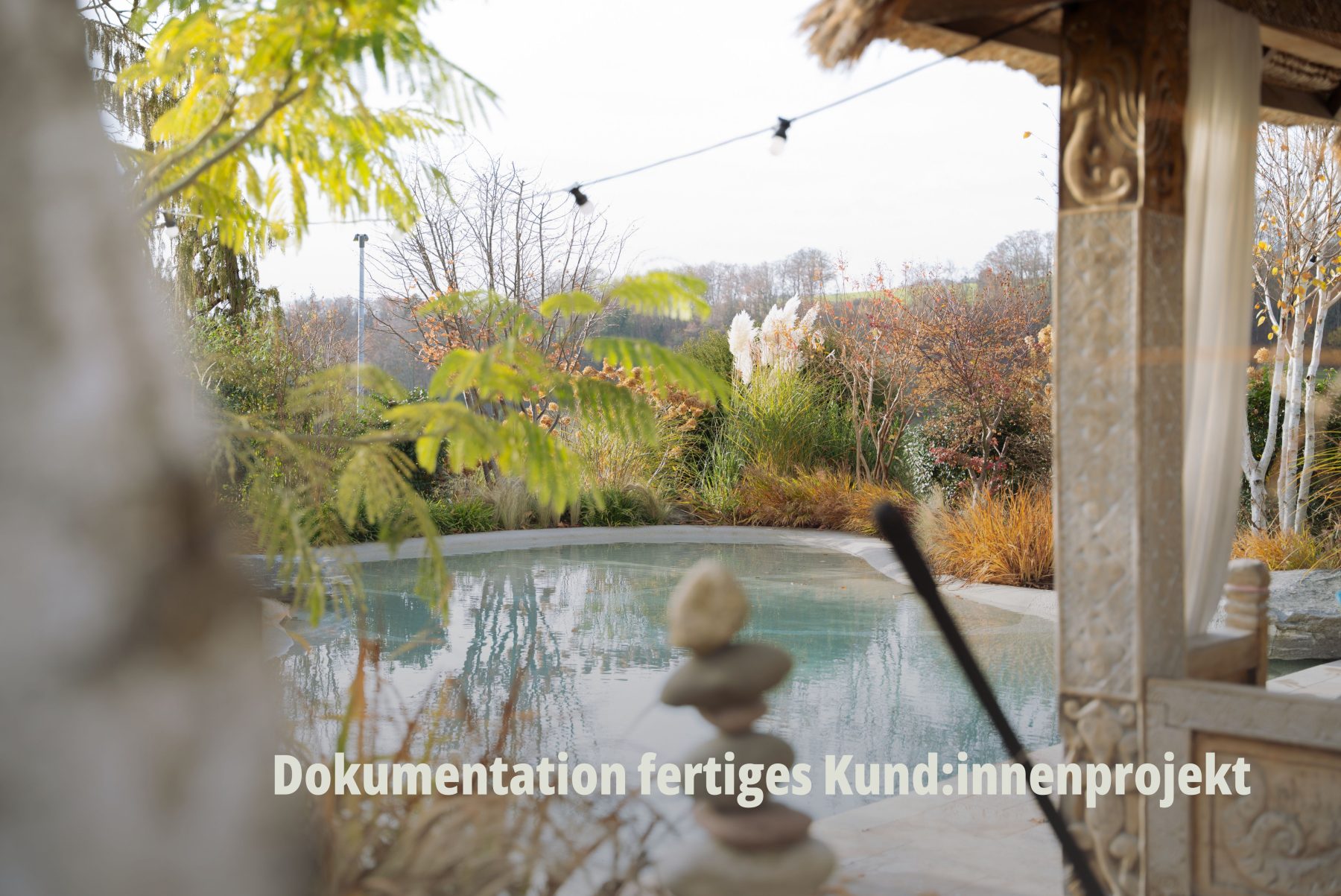 Stimmungsvolle Landschafts- und Gartenfotografie: Blick durch herbstliche Bäume auf einen eleganten Poolbereich im Garten. Hochwertige Bildkomposition für Websiten Content von SR-STUDIOS; Vögtli Gartenbau. | SR-STUDIOS